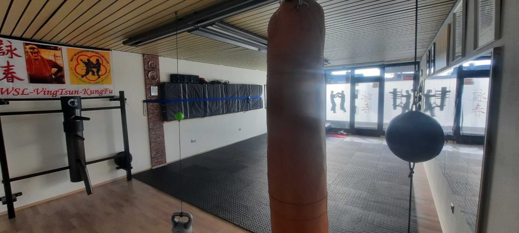 Ein Fitnessraum mit einem Boxsack und einer Trainingsfläche im Hintergrund.