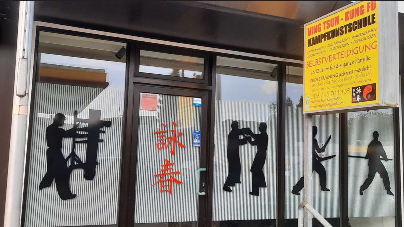 Fenster mit Silhouetten von Kämpfern und einem chinesischen Schriftzeichen.