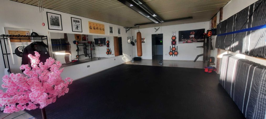 Ein heller Raum mit Matten, Trainingsgeräten und einer rosa Blütenbaum-Dekoration.