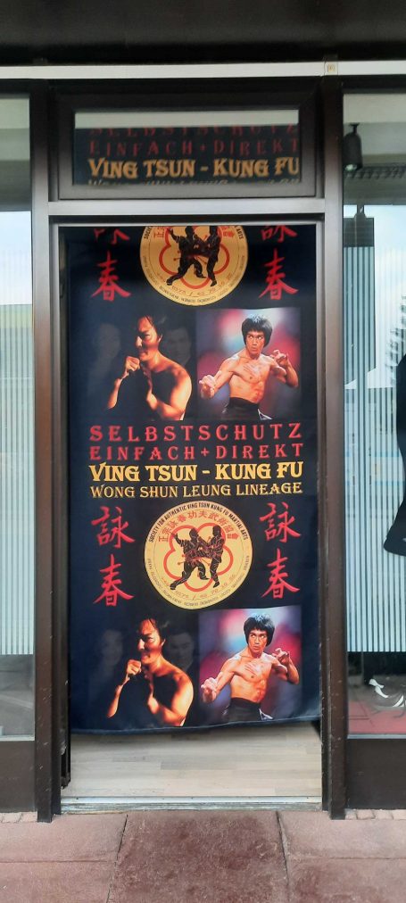 Plakat für eine Kampfkunstschule mit Bildern von Kämpfern und chinesischen Schriftzeichen.